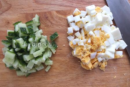 Нарежьте огурцы и яйца кубиками.